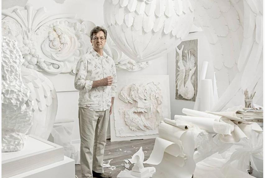 Man standing in room full of white 3D artwork