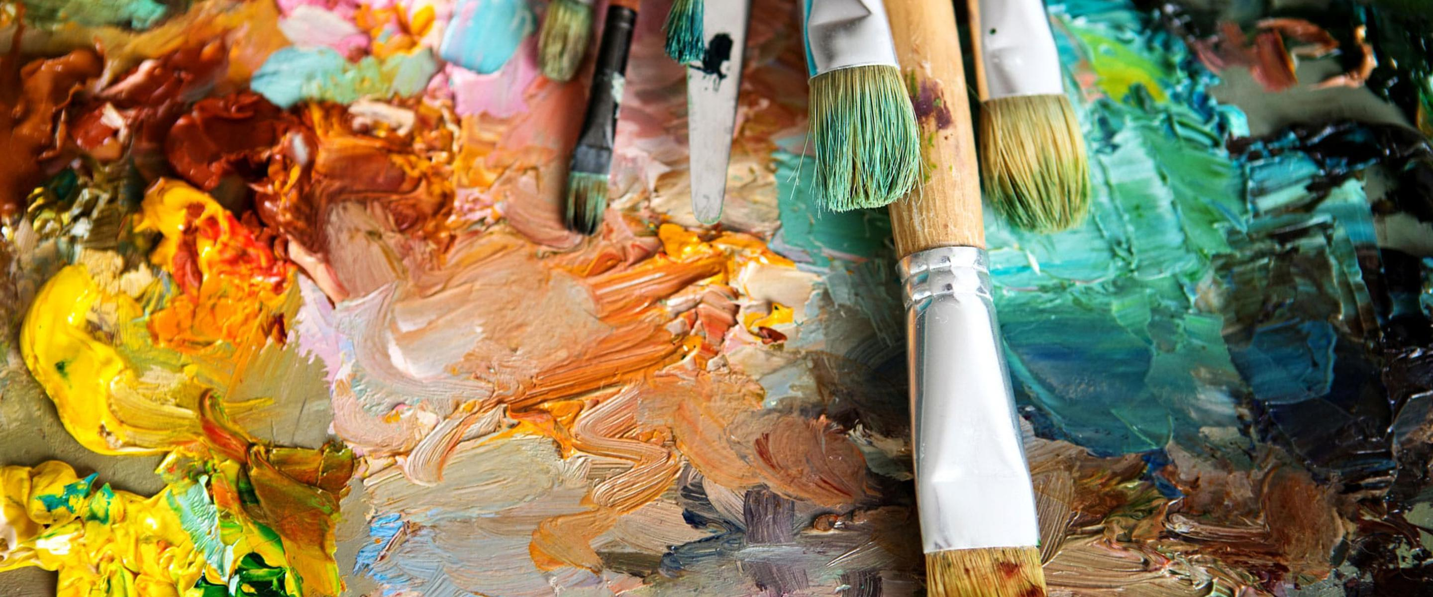 Different sized paint brushes lying on top of an abstract painting
