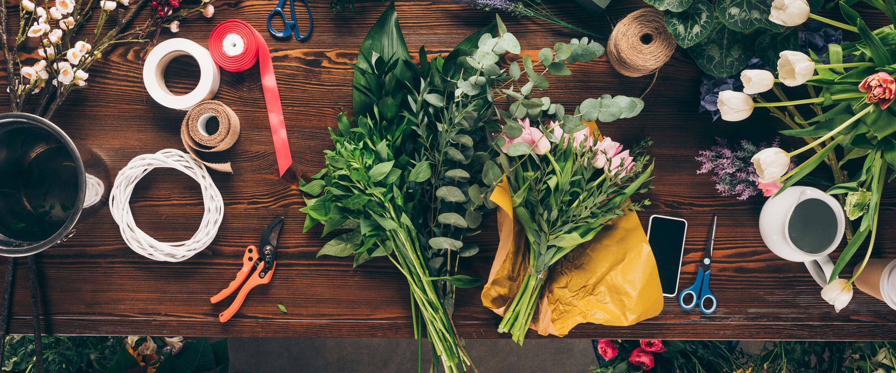 A bird's-eye view of flowers being trimmed and tied together for a bouquet 