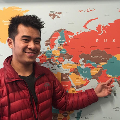 Melbourne Polytechnic international student pointing to a world map.