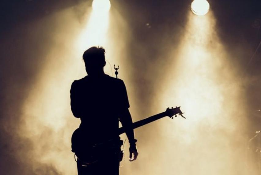 Silhouette of performer with a guitar and fog