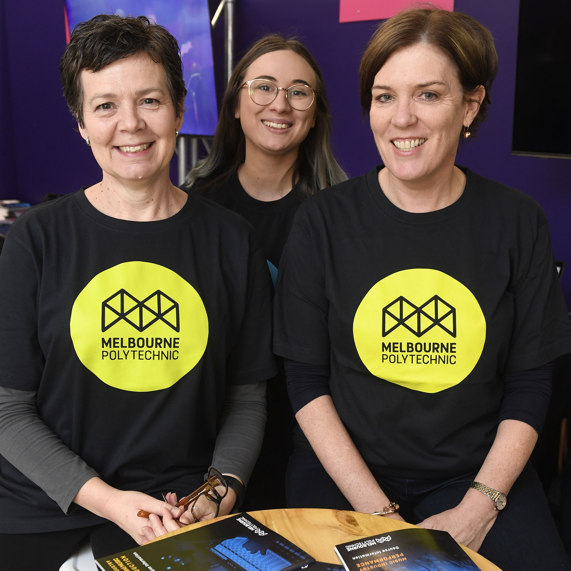 Three people smiling and wearing t-shirts with Melbourne Polytechnic logos 