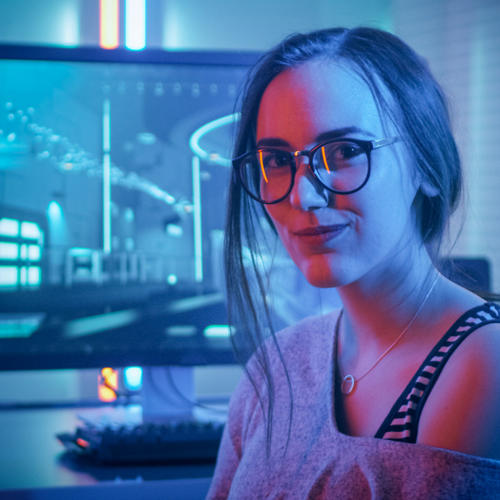 Information technology student posing for photo, with screen monitor behind her.