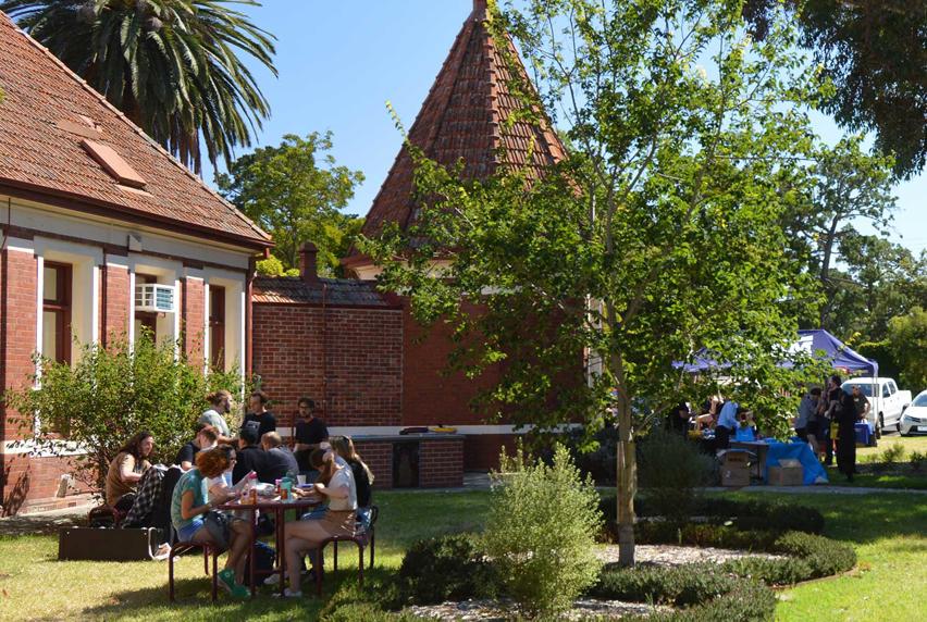 Students sitting outside in the sun on picnic bench eating and socialising at Fairfield campus