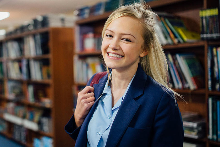 high school student in the library and smiling
