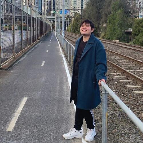 International student Eric Wong in overcoat standing by train rails